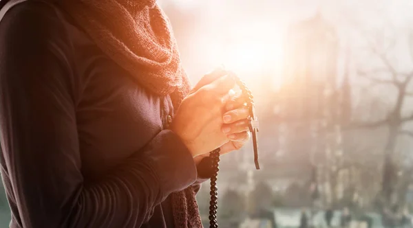 Religione cristiana e concetto di speranza. Mani di donna che pregano con rosario e croce di legno — Foto Stock