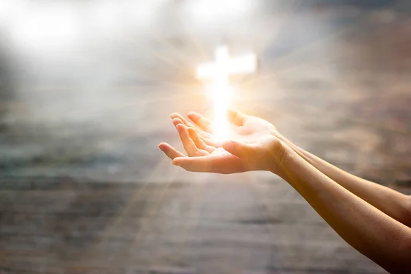 Femme avec croix blanche dans les mains priant pour la bénédiction de Dieu sur fond de lumière du soleil — Photo