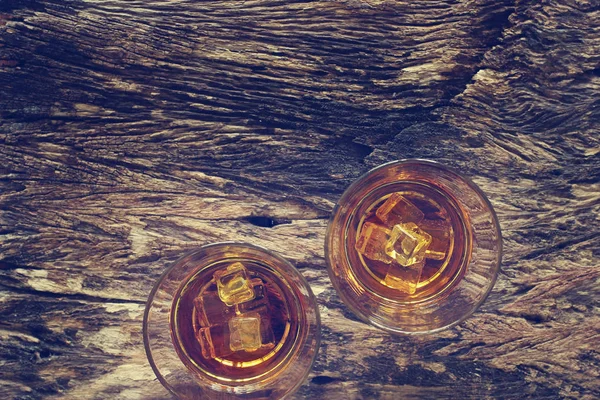 Bicchieri di whisky bourbon con ghiaccio su sfondo texture in legno — Foto Stock