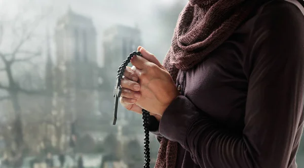 Mujer rezando con rosario y cruz de madera sobre fondo de iglesia . — Foto de Stock