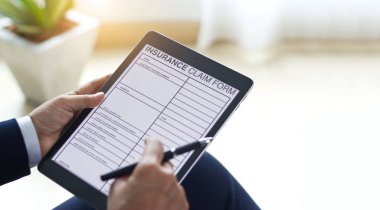 İşadamı belgeyi kontrol ediyor ve sigorta talep formunu dolduruyor