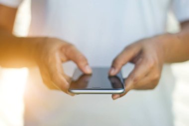 Ön manzara, kadın elleri günbatımında cep telefonu kullanıyor.