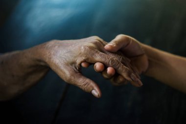 Alzheimer ve Parkinson hastası olan annesinin elini tutan bir kız..