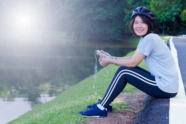 Asian Sport Woman with Cycling Helmet Acting near the Lagoon