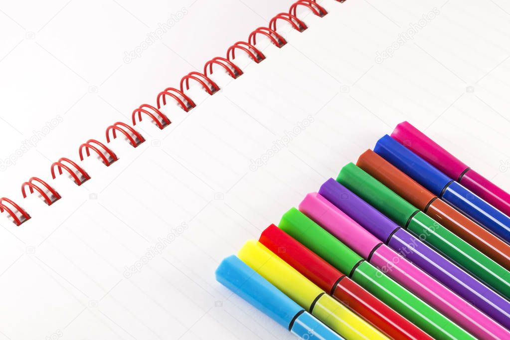 Colorful markers on white notebook
