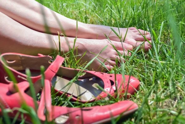 Kvinnliga fötter och gräs Stockbild