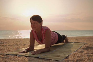 Parkta yoga yapan olgun bir kadın.