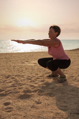 Parkta yoga yapan olgun bir kadın.