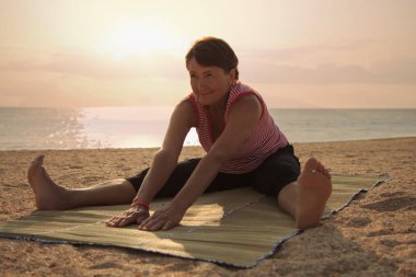 Parkta yoga yapan olgun bir kadın.