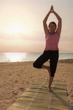 Parkta yoga yapan olgun bir kadın.