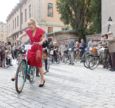 Güzel bir kadın giyinmiş eski moda kırmızı elbise Bisiklete binme