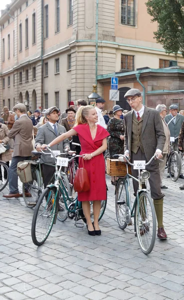 Smiling woman dressed in a red dress leading bicycles — Stock Photo, Image