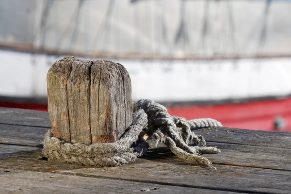 Bollard de madeira, corda e barcos de pesca no fundo — Fotografia de Stock