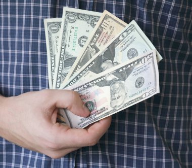 Bize Doları banka notları, mavi tişört arka planda tutan el. Kısa odak derinliği