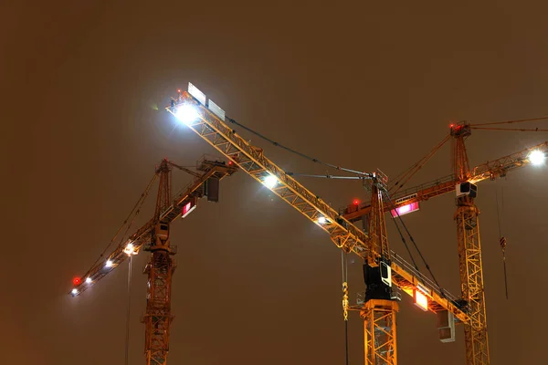 Tres grúas amarillas en la luz amarilla de la noche —  Fotos de Stock