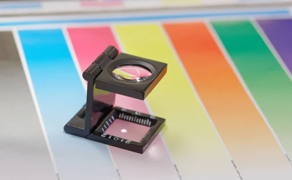 Magnifier or printer's loupe sits on a colorful CMYC test sheet — Stock Photo, Image