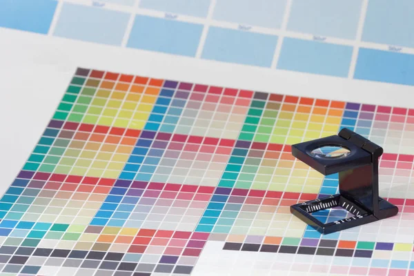Förstoringsglaset eller skrivarens lupp sitter på en färgglad Cmyk Testark — Stockfoto