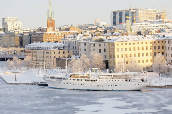 STOCKHOLM - JAN 08, 2017: Beautiful boat and old buildings at Riddarholmen lit with warm light a cold winter morning, ice on the sea. January 08, 2017 in Stockholm, Sweden