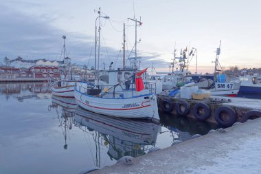 Stockholm - 31 Ocak 2017: Birçok balıkçı teknesi sabah güneşinde kırsal bölgede. Arka planda kırmızı evler var. 21 Ocak 2017, Grisslehamn, İsveç