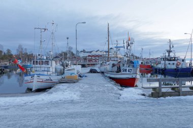 Stockholm - 31 Ocak 2017: Birçok balıkçı teknesi sabah güneşinde kırsal bölgede. Arka planda kırmızı evler var. 21 Ocak 2017, Grisslehamn, İsveç