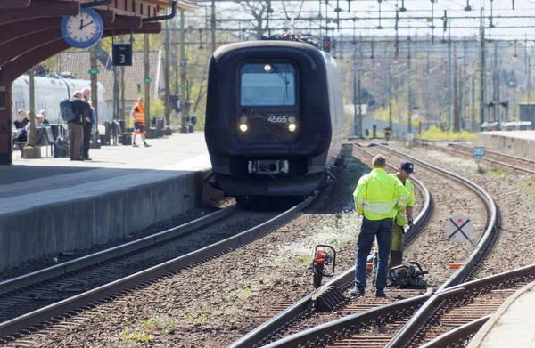 Tracklayer arbetar med järnvägen när ett tåg anländer — Stockfoto