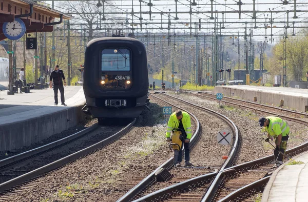 Tracklayer arbetar med järnvägen när ett tåg anländer — Stockfoto