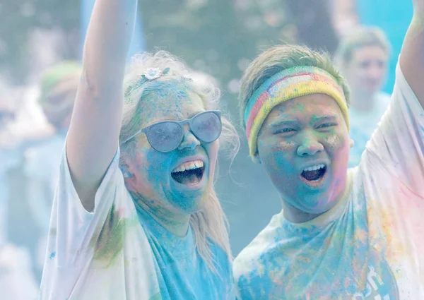Teenagers covered with color dust rasing arms in the air — Stock Photo, Image