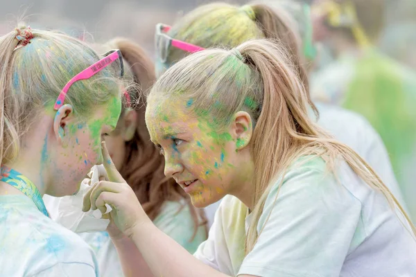 Duas meninas adolescentes cobertas com poeira de cor colorida ajudando cada — Fotografia de Stock