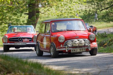 Stockholm, İsveç - 22 Mayıs 2017: Red Austin Cooper ve bir Mercedes klasik araba Stockholm 'deki Djurgarden' daki güzel ormanlarda Gardesloppet halk yarışında yokuşta. 22 Mayıs 2017 Stockholm, İsveç
