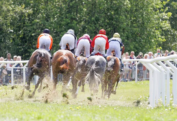 Visão traseira de jóqueis montando cavalos de corrida em uma curva — Fotografia de Stock