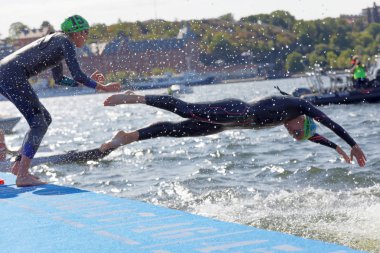 STOCKHOLM - AUG 26, 2017: Two female swimmer wearing black swimsuit  jump into the water in the Women's ITU World Triathlon series event August 22, 2017 in Stockholm, Sweden clipart