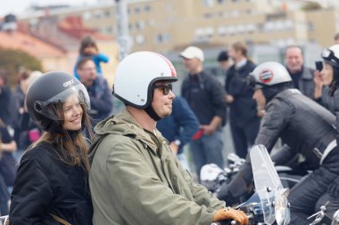 STOCKHOLM, SWEDEN - SEPT 02, 2017: Smiling mods girl and man driving old fashioned vespa scooter at the Mods vs Rockers event at the Saint Eriks bridge, Stockholm, Sweden, September 02, 2017