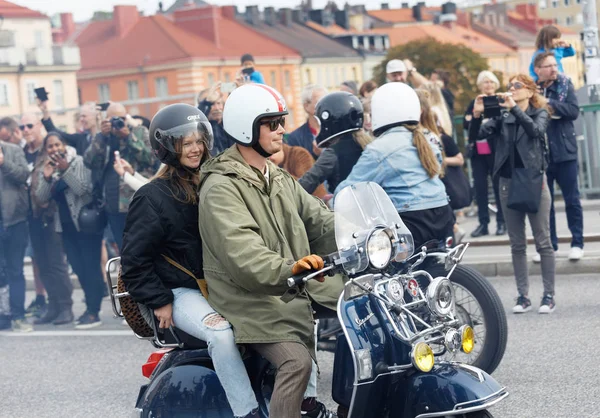 STOCKHOLM, SWEDEN - SEPT 02, 2017: Smiling mods girl and man driving old fashioned vespa scooter at the Mods vs Rockers event at the Saint Eriks bridge, Stockholm, Sweden, September 02, 2017