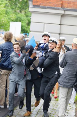 Stockholm, İsveç - 13 Haziran 2017: Mezuniyet töreninde Norra Real okulundan mezun olduktan sonra arkadaşını taşıyan takım elbiseli mutlu öğrenciler, 13 Haziran 2017 Stockholm, İsveç