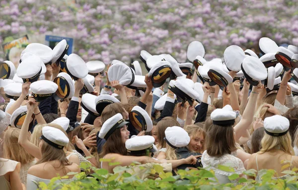 Sonriendo estudiantes graduados, hermoso arbusto llilac en el backgr — Foto de Stock