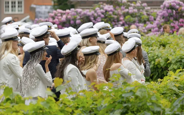 Mezun olduktan sonra beyaz mezuniyet kapaklar giymiş mutlu gençler — Stok fotoğraf