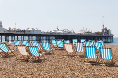 Brighton, İngiltere - 17 Haziran 2017: Güneşli bir günde Brighton rıhtımındaki çakıl taşı plajında klasik boş şezlonglar. 17 Haziran 2017, Brighton, İngiltere