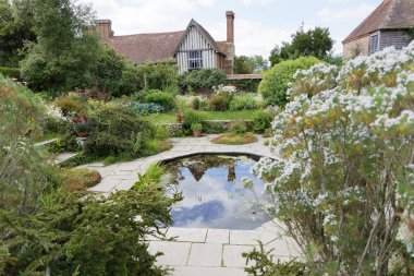 Northiam, İngiltere - Haziran 06, 2017: Arka planda çiçekler, bitkiler ve binalar olan gölet. Haziran 06, 2017 Northiam, İngiltere