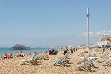 BRIGHTON, GREAT BRITAIN - JUN 17, 2017: Sunbathing people and deckchairs on the Brighton beach, West pier in the background. June 17, 2017 in Brighton, Great Britain