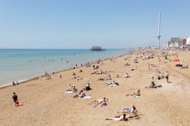 Brighton, İngiltere - 17 Haziran 2017: Brighton plajında güneşlenen insanlar, arka planda batı iskelesi. 17 Haziran 2017, Brighton, İngiltere