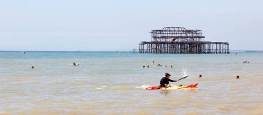 Bir kano ve güneşlenme insanlar Brighton Plajı dışında arka planda West pier Brighton, Büyük Britanya - 17 Haziran 2017: adam. 17 Haziran 2017 Brighton, Büyük Britanya