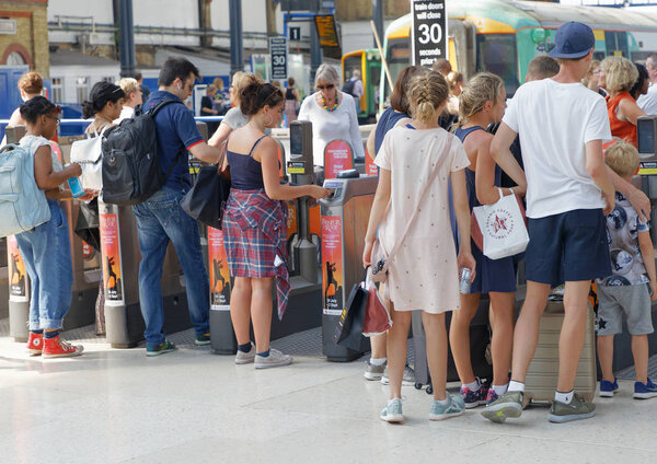 Люди, проходящие через зону оплаты на вокзале в Брайтоне
