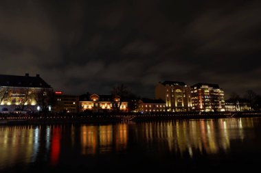 Norrkoping, İsveç - 31 Aralık 2017: Güzel Motala Strom nehrinin Nightscape 'i ve İsveç' in orta Norrkoping 'indeki sulara yansıyan binalar, 31 Aralık 2017