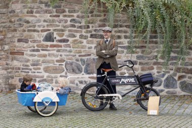 Stockholm - 23 Eylül 2017: eski moda tüvit kıyafetler ve bisiklet bir arabası ile iki çocuğunu Tweed olay Bisiklet taştan bir duvar önünde ile 23 Eylül 2017 Stokholm, İsveç'te giymiş baba