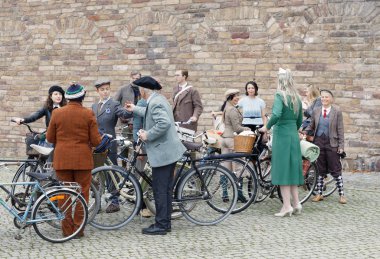 Stockholm - 23 Eylül 2017: taştan bir duvar önünde retro Bisiklet Bisiklet Tweed olay 23 Eylül 2017 Stokholm, İsveç'te holding eski moda yün elbise giymiş insanlar