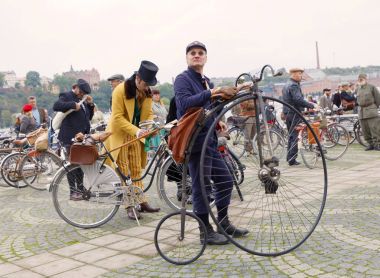Yüksek wheeler veya penny-farthing Bisiklet ve insanlar eski giymiş