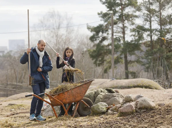 Father and daughter putting straw in a wheelbarrow in the pastur — Stock Photo, Image