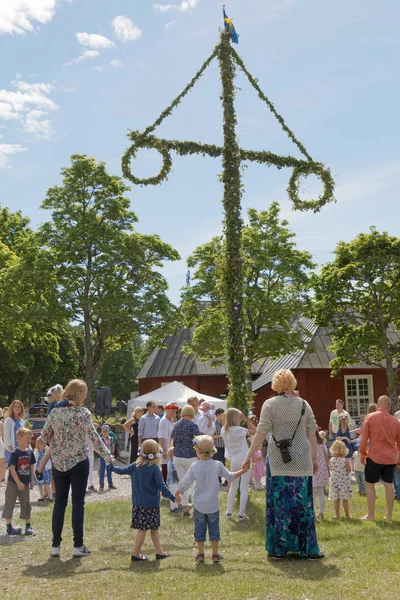 Niños y adultos bailando y tomados de la mano alrededor del Maypole — Foto de Stock