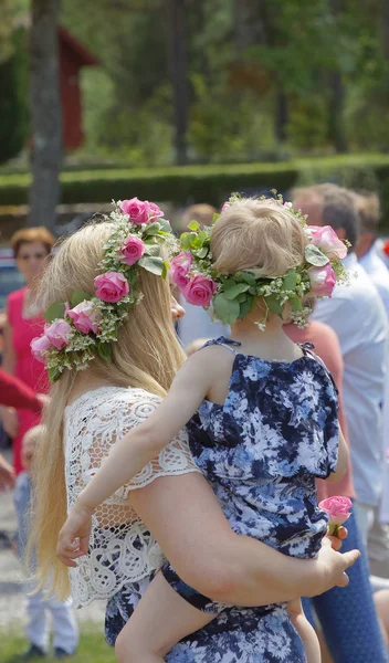 Madre sosteniendo a su hijita, ambas teniendo flores en su — Foto de Stock
