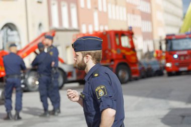 İtfaiye kamyonlarının önünde çalışan İsveçli polis memurları